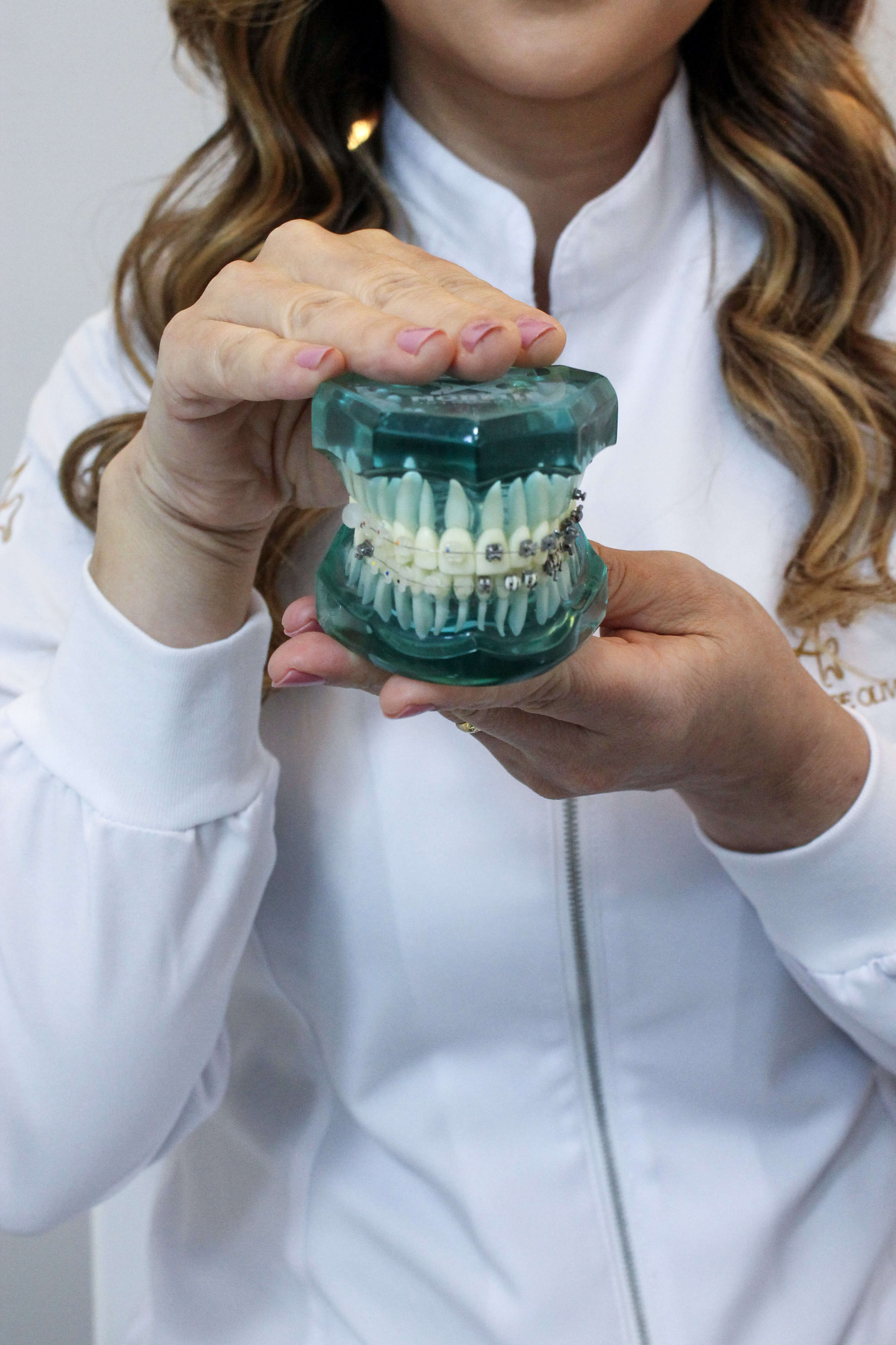Modelo dentário transparente com aparelho ortodôntico nas mãos da Dra. Adriana